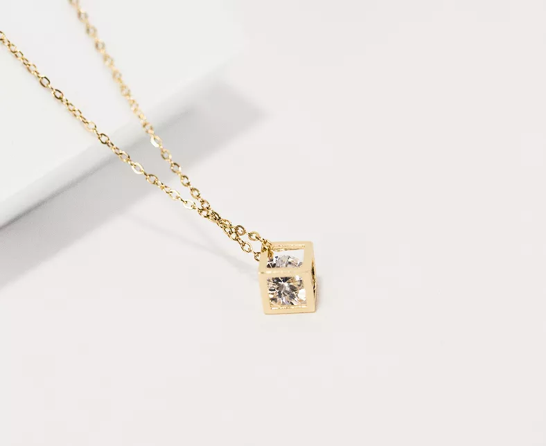 Minimalist gold square pendant necklace with two small round crystals on fine chain against white background in clean product photography